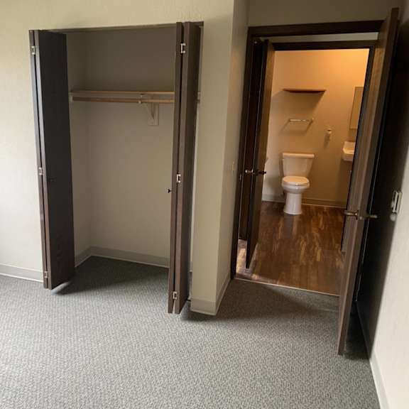 a room with a carpeted floor and a closet with a door open to a bathroom.