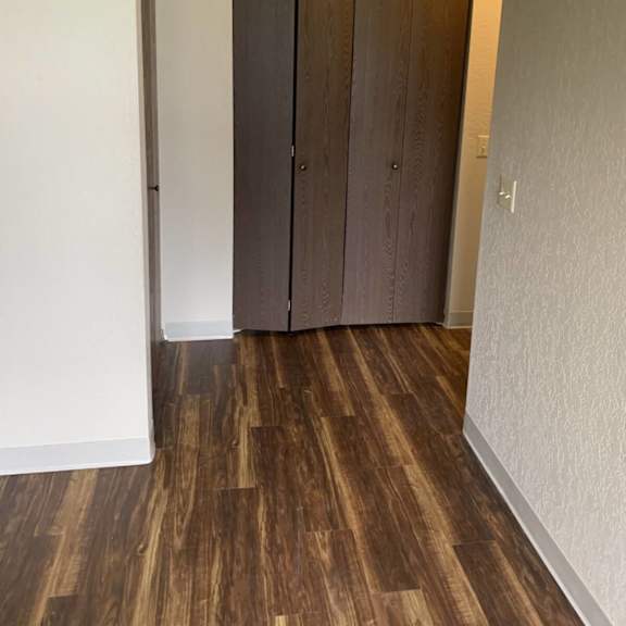 a room with a brown wood floor and a white wall.
