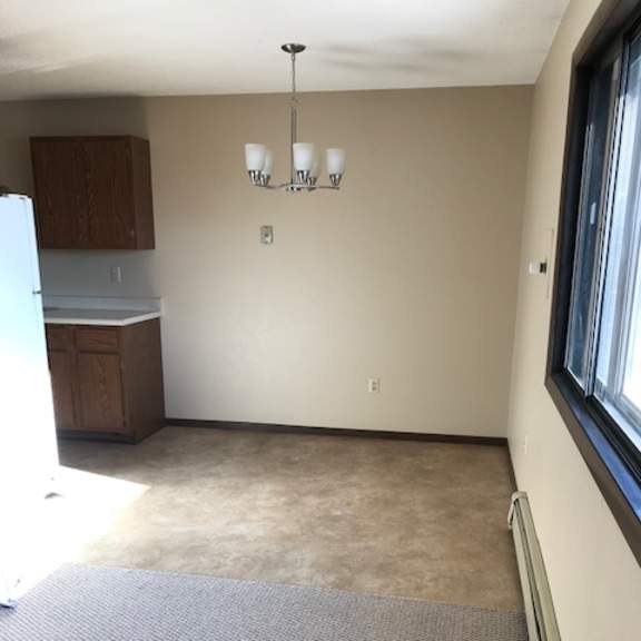 a room with a grey carpet and a chandelier.