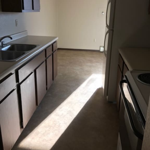 a kitchen with a sink, refrigerator, and cabinets.