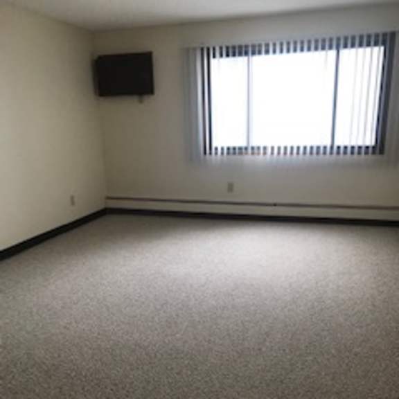 a room with a carpeted floor and a window with blinds.