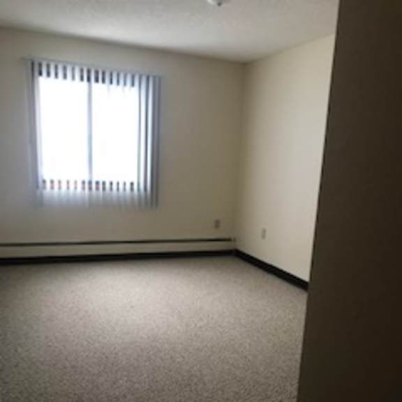 a room with a carpeted floor and a window with blinds.