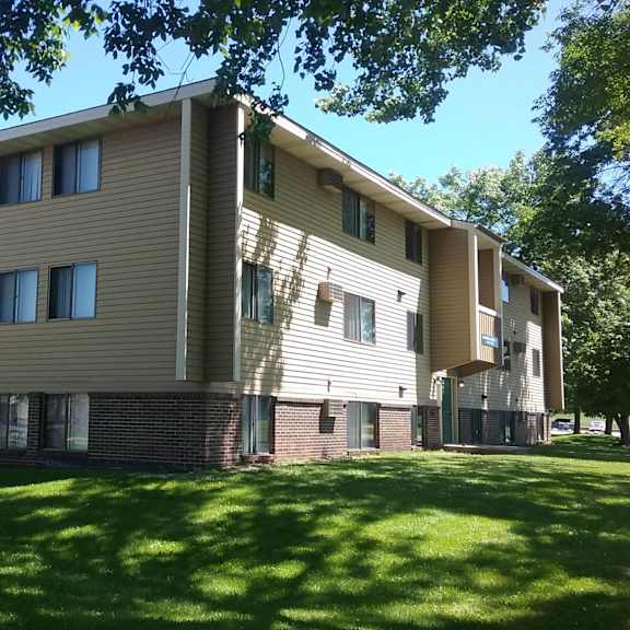 a large apartment building with a green lawn in front.