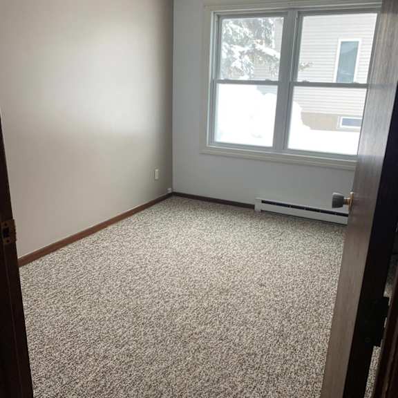 a room with a carpeted floor and a window showing a snowy scene outside.