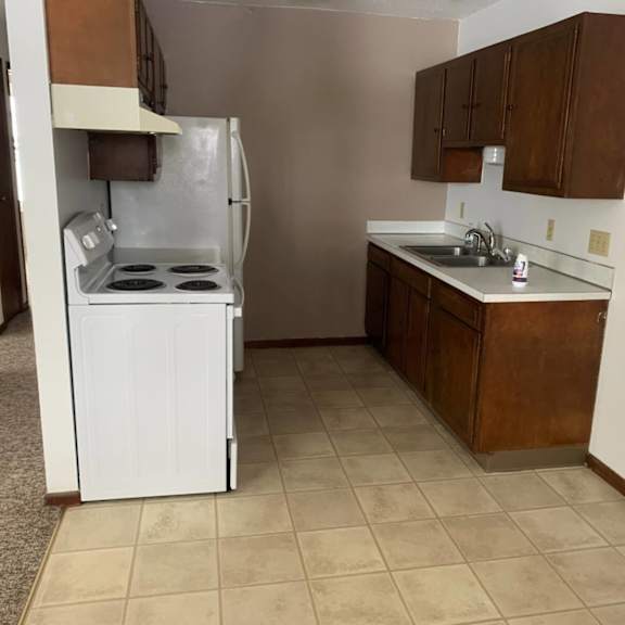 a kitchen with a white refrigerator and brown cabinets.