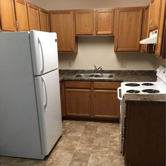 a kitchen with a white refrigerator and a white stove top oven.
