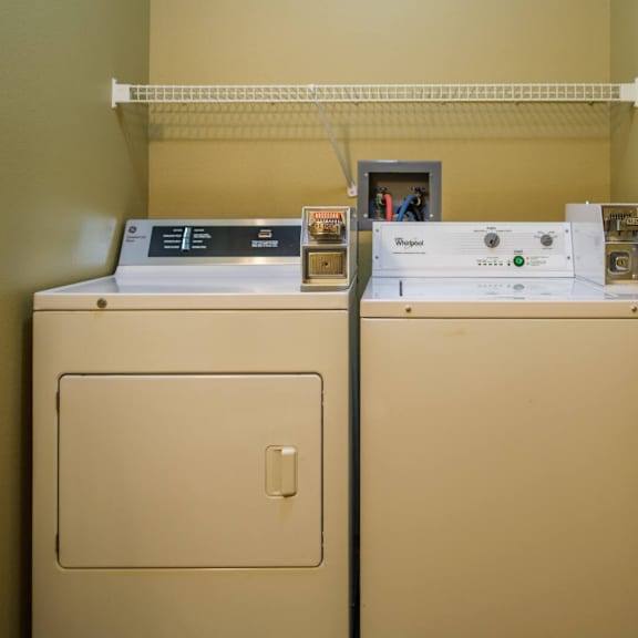 two tan appliances with a shelf above them.