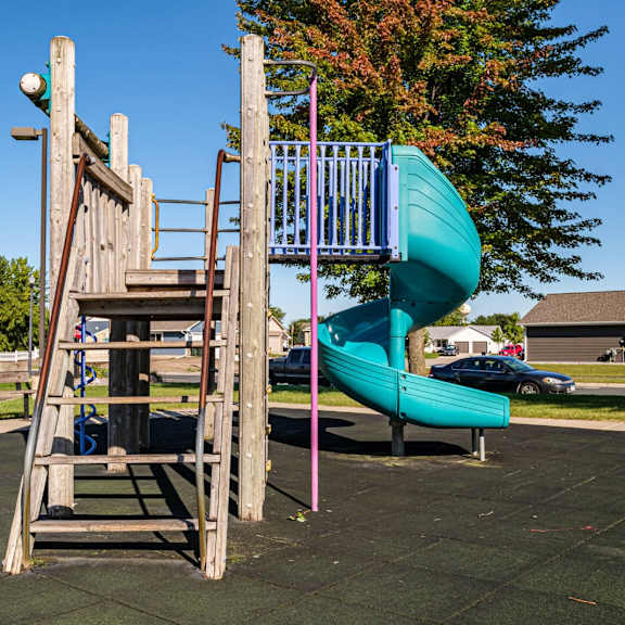 a playground with a green slide and a wooden structure.