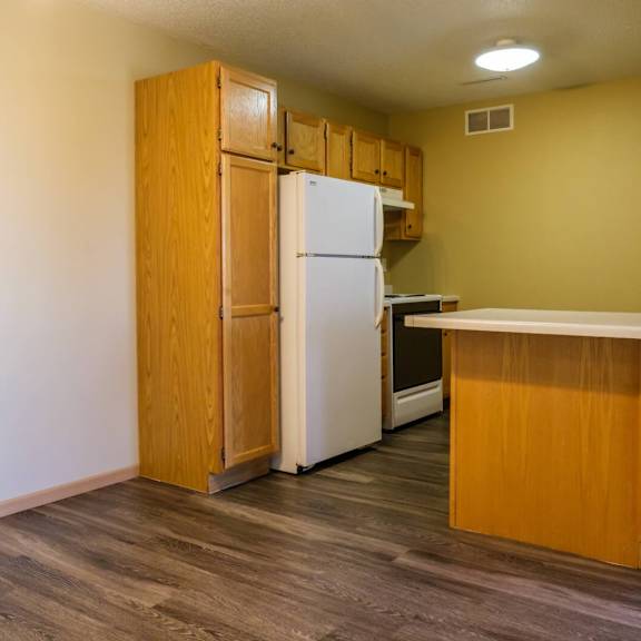 a kitchen with a white refrigerator and wooden cabinets.