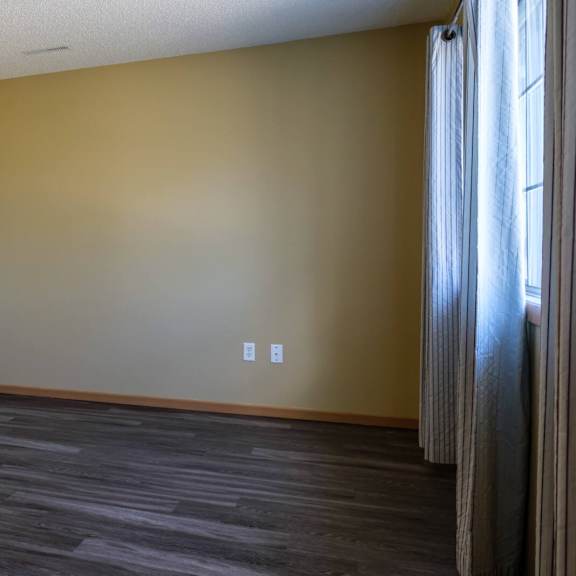 a room with a wooden floor and a window with curtains.