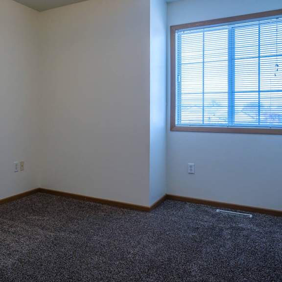 a room with a carpeted floor and a window with blinds.