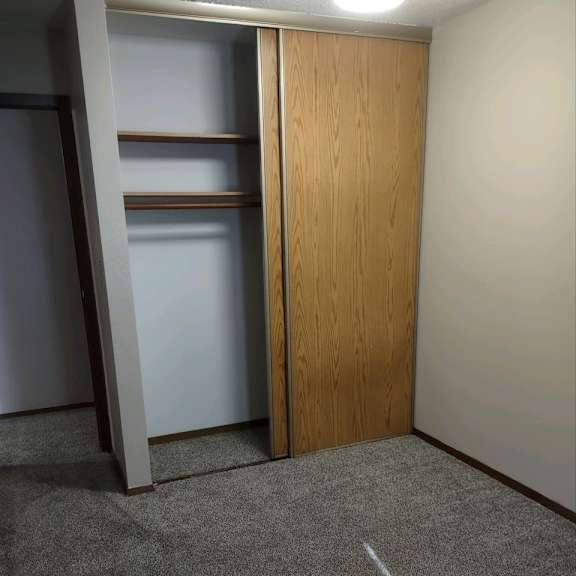 a room with a wooden door and a grey carpet.