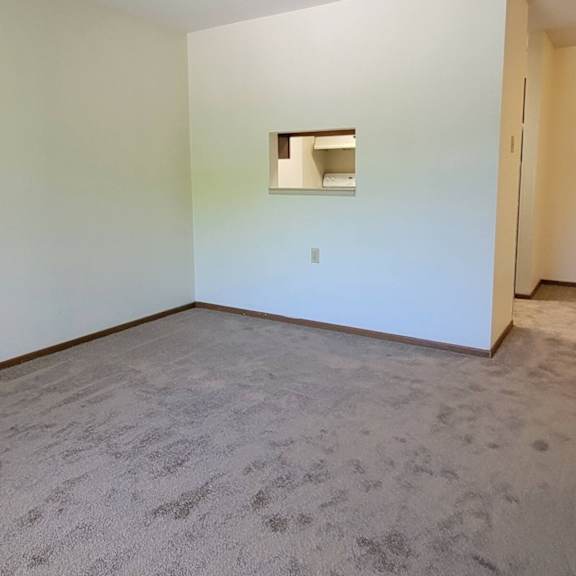 a room with a carpeted floor and a small window on the wall.