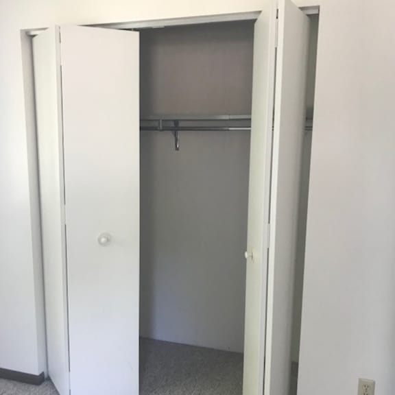 a white closet with a door open and a shelf above it.