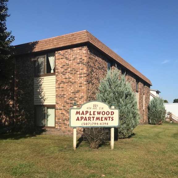 a sign for maplewood apartments stands in front of a brick building.