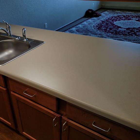 a kitchen counter with a sink and brown cabinets.