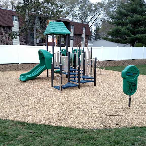 a playground with a green slide and a wooden swing set.