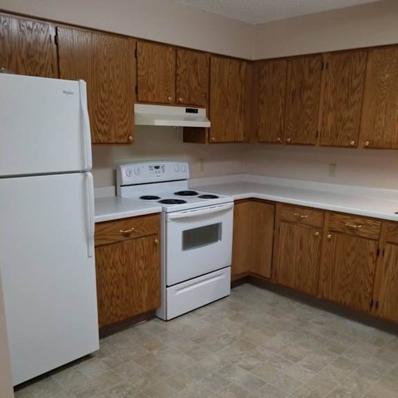 a kitchen with white appliances and wooden cabinets.
