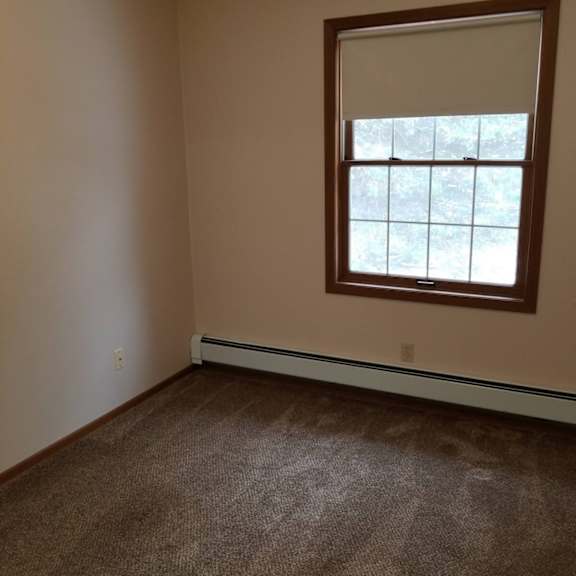a room with a window and a carpeted floor.