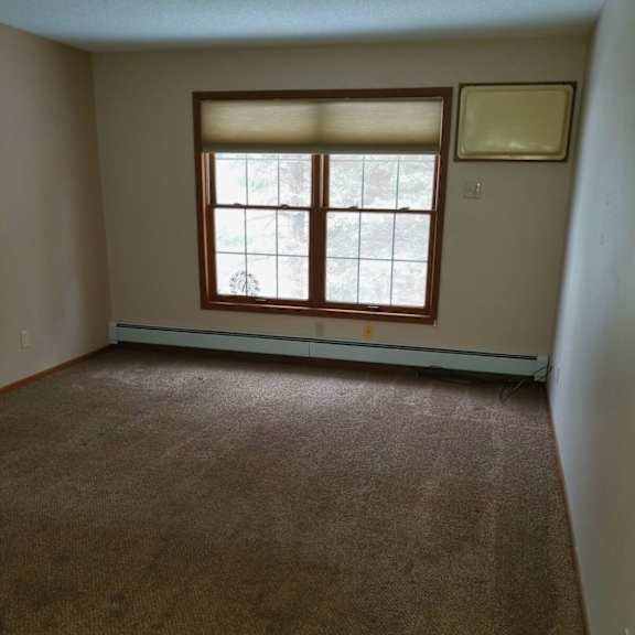 a room with a carpeted floor and a window with blinds.