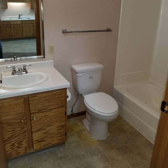 a white toilet sits in a bathroom next to a sink and a bathtub.