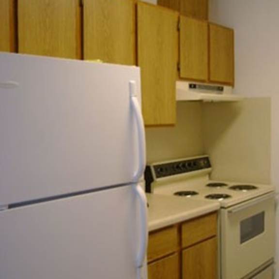 a white refrigerator is in a kitchen with wooden cabinets.