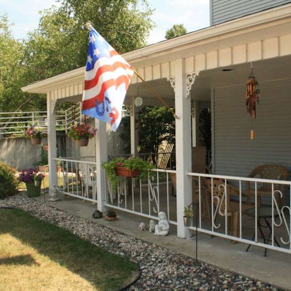 a porch with a flag and chairs.