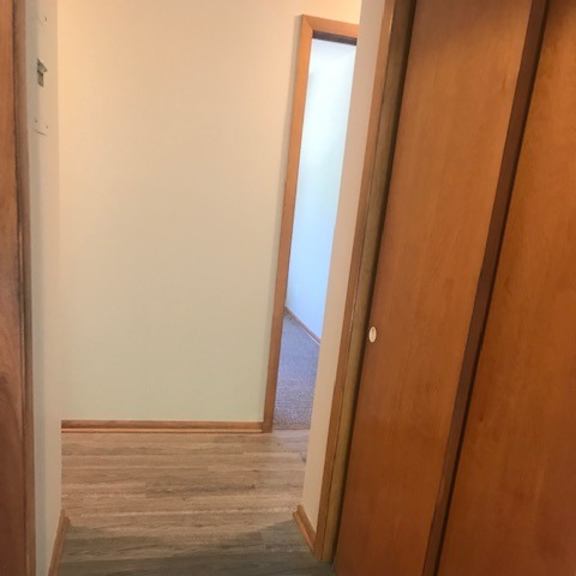 a hallway with a wooden floor and a white wall.