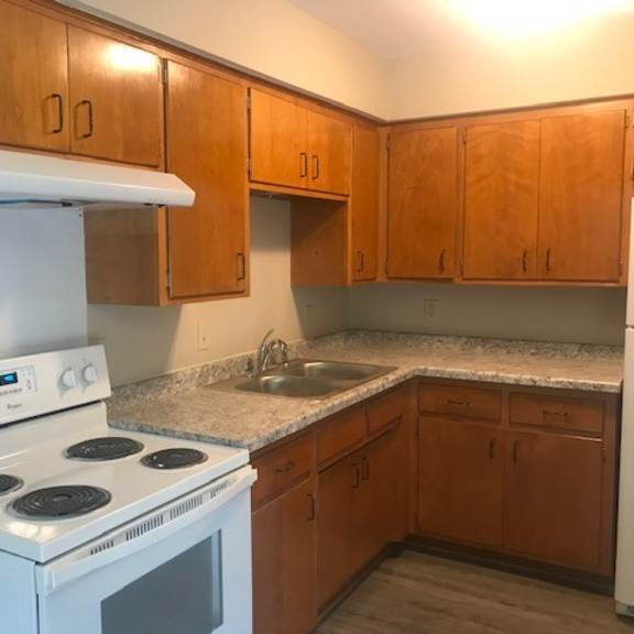 a kitchen with a white stove and wooden cabinets.