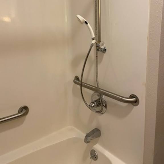 a shower with a silver faucet and a silver shower head.