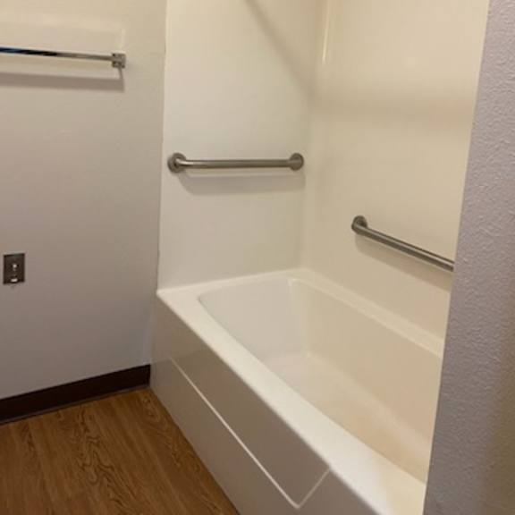 a white bathroom with a white tub and a white door.