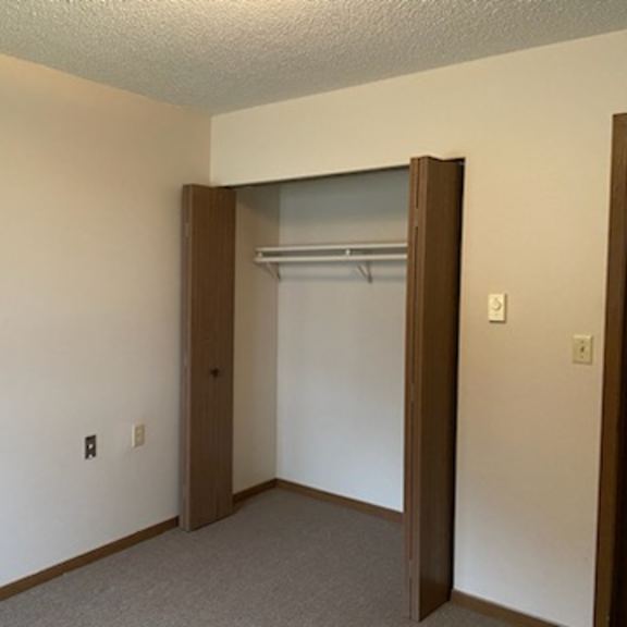 a room with a white wall and a brown door.