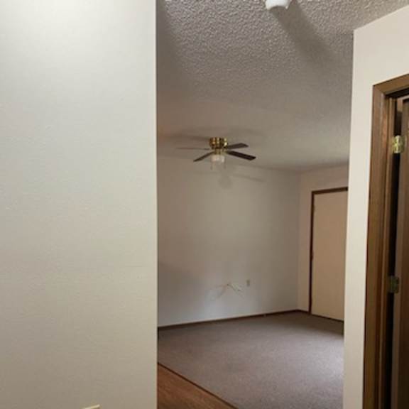 a room with a ceiling fan and a door.