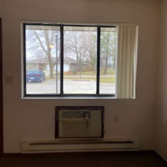 a window with a white curtain and a white air conditioner unit below it.