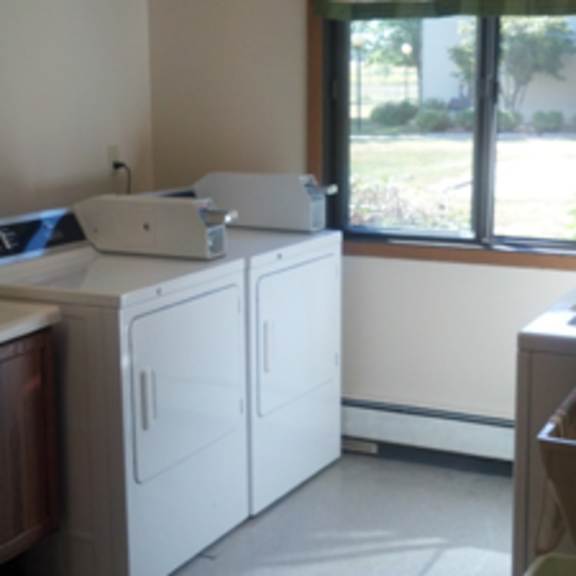 a white fridge and cupboard in a room with a window.