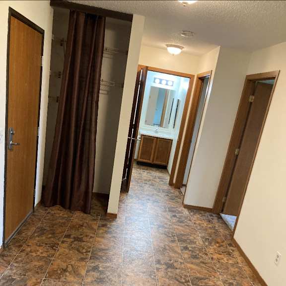 a hallway with a brown tile floor and a brown door.