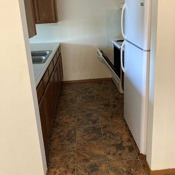 a kitchen with a white refrigerator and brown cabinets.