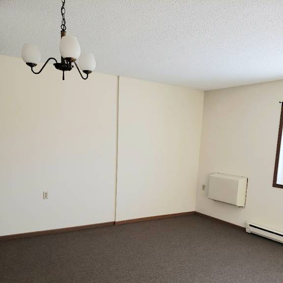 a room with a carpeted floor and a chandelier hanging from the ceiling.