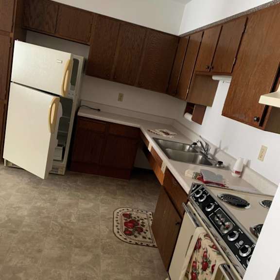 a kitchen with a white refrigerator, a stove with a towel on it, and a sink.