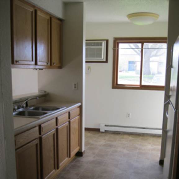 a kitchen with brown cabinets and a window.