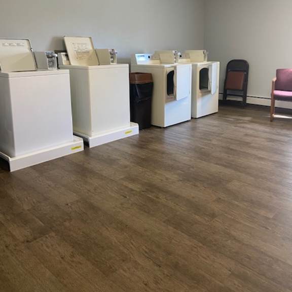 a room with a row of washing machines and a chair.