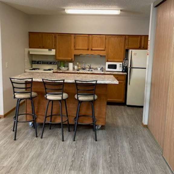 a kitchen with a table and chairs in front of a refrigerator.
