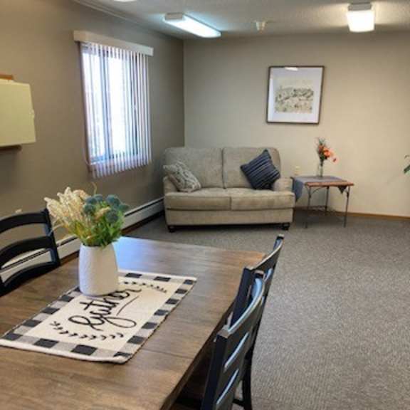 a conference room with a couch, chairs, and a table with a vase of flowers on it.