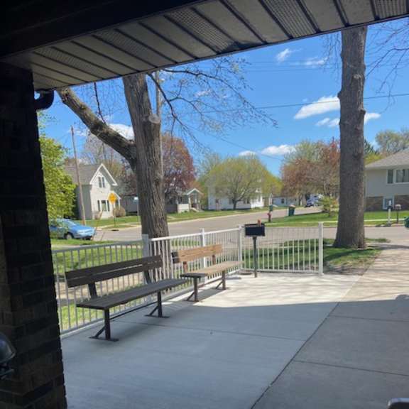 a bench is on a concrete patio under a roof.