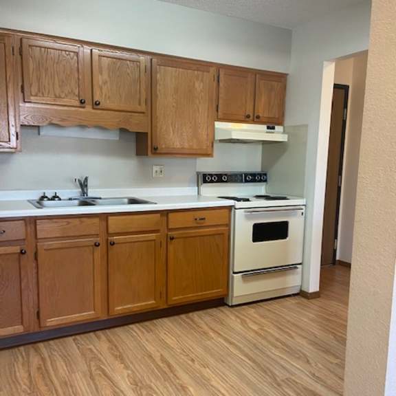 a kitchen with wooden cabinets and a white stove top oven.