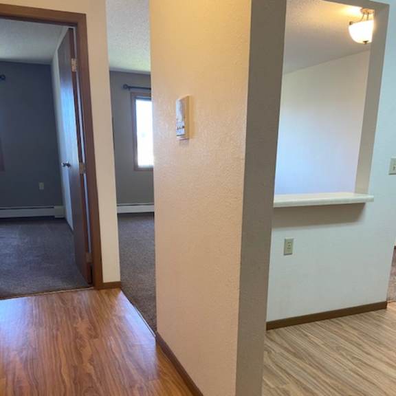 a hallway with wood flooring and white walls.