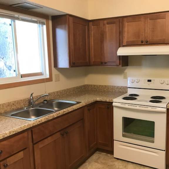 a kitchen with a white stove and brown cabinets.