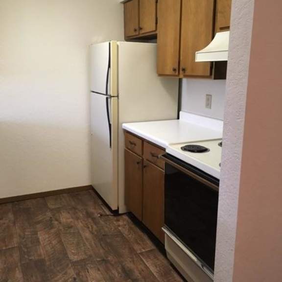 a kitchen with a refrigerator, oven, and wooden cabinets.