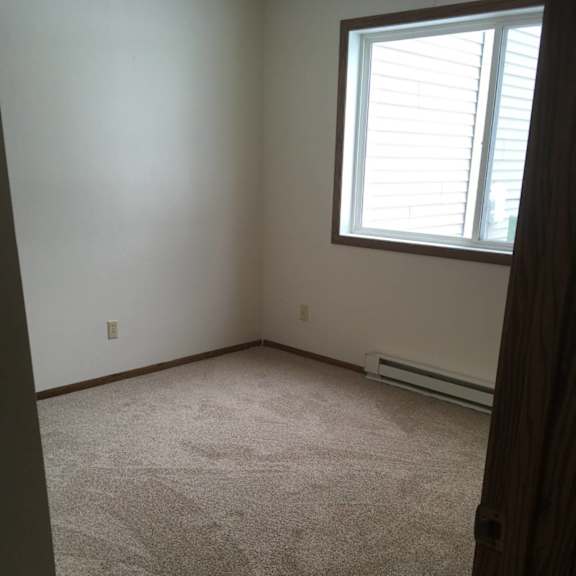 a room with a carpeted floor and a window with blinds.