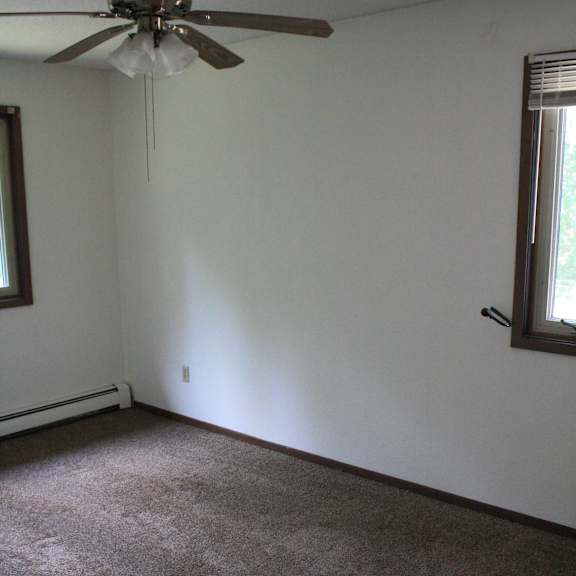 a room with a ceiling fan and carpeted floor.